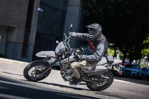 Three-quarter front angle of a person turning down a street on a motorcycle. opens in a new window