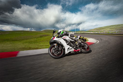Three-quarter front angle of a person riding a motorcycle on a racetrack. opens in a new window