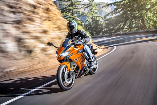 Three-quarter front angle of a person making a turn around a rocky mountain on a highway. opens in a new window