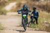 Front angle of a young adult riding an electric balance bike over small dirt bumps.