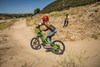 Three-quarter rear angle of a young adult riding an electric balance bike around a corner. 