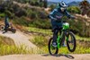 Three-quarter front angle of a young adult riding an electric balance bike up a small dirt hill.