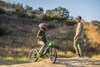 Side angle of a young adult sitting on an electric balance bike parked talking to their parent. 