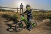 Side angle of a young adult sitting on an electric balance bike parked. 