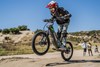 Three-quarter front angle of a young adult riding an electric balance bike with the front wheel off the ground.