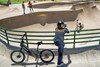 Overhead angle of a young adult standing next to an electric balance bike taking video of their friends.