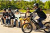 Side angle of a young adult riding an electric balance bike with friends nearby.