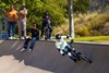 Front angle of a young adult riding an electric balance bike with friends in the background.