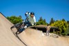 Front angle of a young adult riding an electric balance bike up the outer edge of the skate park.