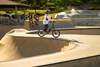 Side angle of a young adult riding an electric balance bike in a skate park.