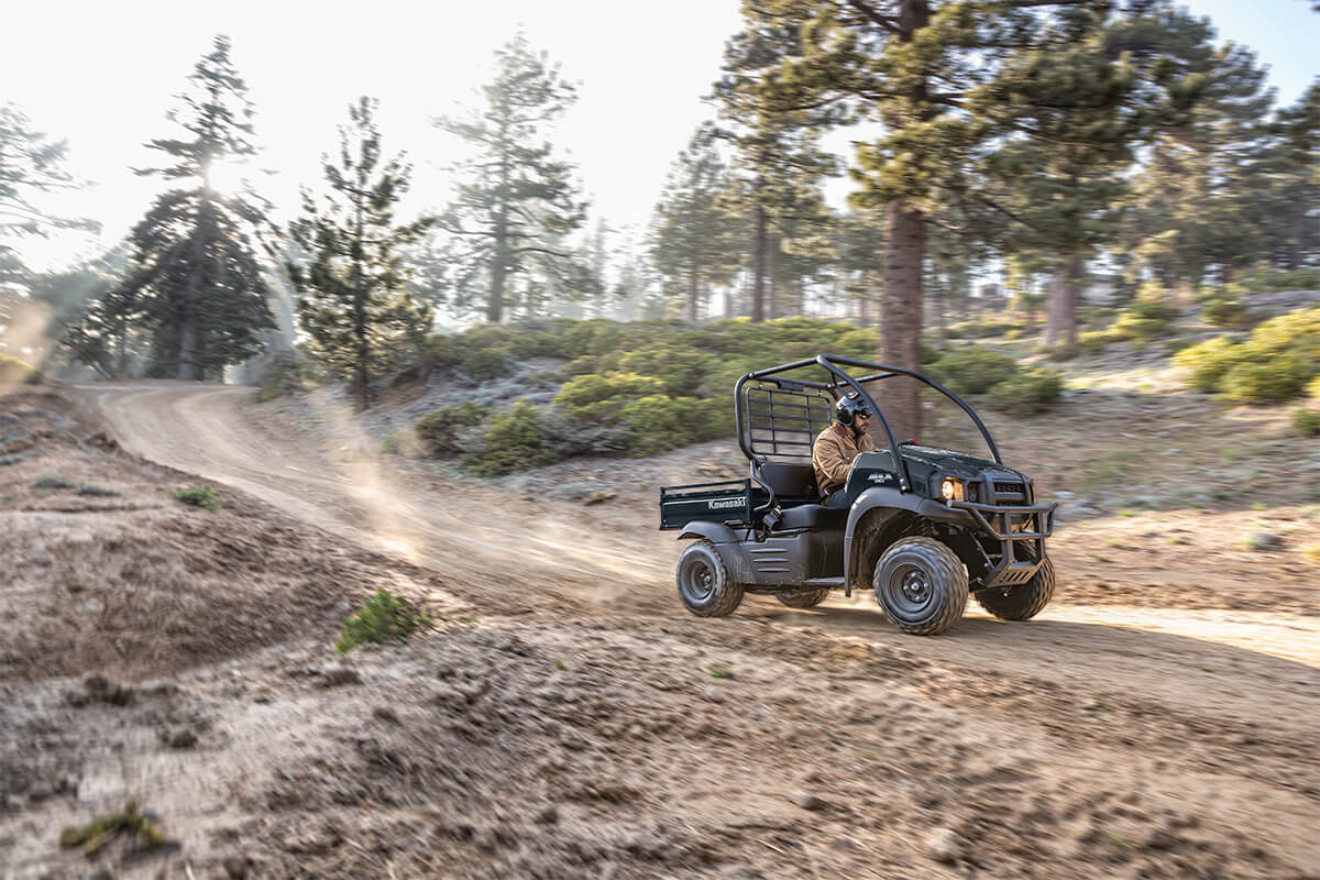 Three-quarter front angle of a person driving a side x side on a dirt trail.