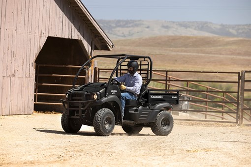 Three-quarter front angle of a person driving a side x side on a ranch. opens in a new window
