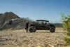 Profile view of a side x side parked off-road with a person standing behind.