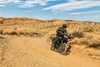 Three-quarter front angle of a person riding a motorcycle on a dirt road.