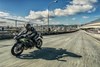 Side angle of a person riding a motorcycle on a road.