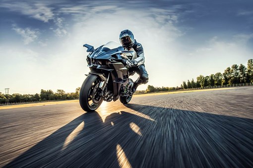 Three-quarter front angle of a person riding a motorcycle on a racetrack. opens in a new window