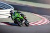 Three-quarter front angle of a person riding a motorcycle on a racetrack.