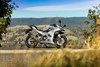 Side angle of a motorcycle parked on the side of a highway.