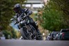 Three-quarter front angle of a person riding a motorcycle on a neighborhood street.