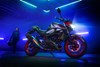 Side angle of a motorcycle staged in a warehouse with blue neon lighting.