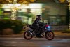 Side angle of a person riding a motorcycle on a city street.