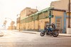  Side angle of a person riding a motorcycle on a rural street.