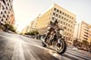 Three-quarter front angle of a person riding a motorcycle on a city street.