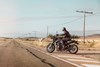  Side angle of a person riding a motorcycle on a rural street.