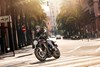 Three-quarter front angle of a person riding a motorcycle on city street.