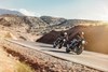 Three-quarter front angle of two people riding motorcycles on highway.