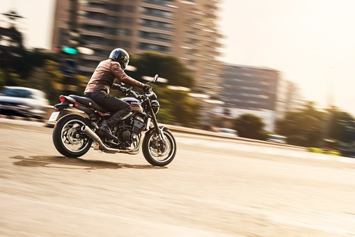 Three-quarter rear angle of a person riding a motorcycle on a city street. opens in a new window
