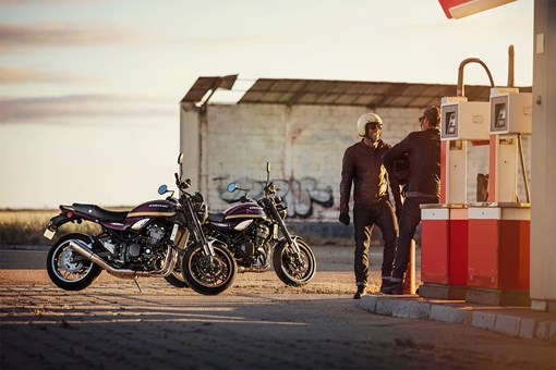 Front angle of two people with their motorcycles in the background. opens in a new window