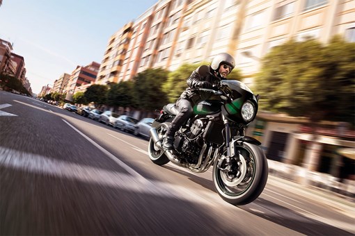 Three-quarter front angle of a person riding a motorcycle on a city street. opens in a new window