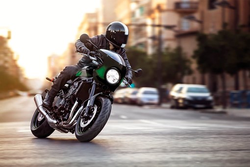 Three-quarter front angle of a person riding a motorcycle on a city street. opens in a new window