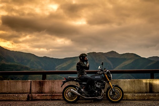 Side angle of a person seated on a parked motorcycle. opens in a new window
