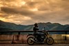 Side angle of a person seated on a parked motorcycle.