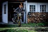 Front angle of a person walking a motorcycle out of the garage.