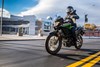 Three-quarter front angle of a person riding a motorcycle on a city street.