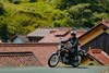 Three-quarter front angle of a person riding a motorcycle on a village road.