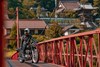 Three-quarter front angle of a motorcycle and rider stopped on a bridge.