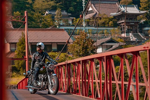 Three-quarter front angle of a motorcycle and rider stopped on a bridge. opens in a new window