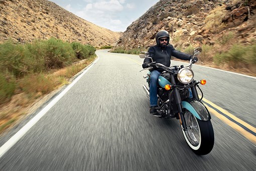 Three-quarter front angle of a person riding a motorcycle on a highway. opens in a new window