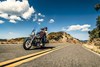 Three-quarter front angle of a person and a passenger riding a motorcycle on a highway.