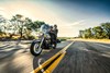 Three-quarter front angle of a person and a passenger riding a motorcycle on a highway.