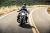 Front angle of a person and a passenger riding a motorcycle on a highway.