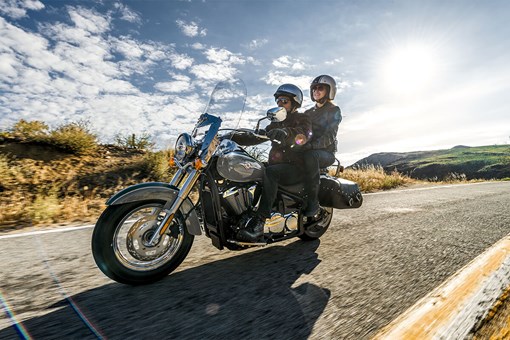 Side angle of a person and a passenger riding a motorcycle on a highway. opens in a new window