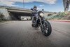 Three-quarter front angle of a person riding a motorcycle on a street near the freeway.