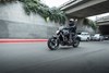 Side angle of a person riding a motorcycle on a city street.