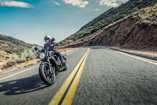 Three-quarter front angle of a person riding a motorcycle on a highway. opens in a new window