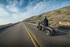 Three-quarter rear angle of a person riding a motorcycle on a highway.